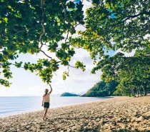 Woman walking under a shady tree on the coastline of Mission Beach Australia