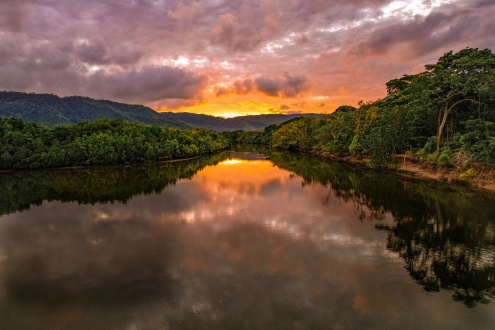 A sunset over the Daintree river with dense surrounding rainforest. 