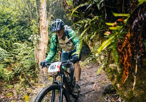 Man riding a bike on a dirt track through the rainforest